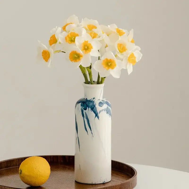 A white ceramic vase with blue splatter paint holding white daffodils from decorbites graffiti ceramic vase collection