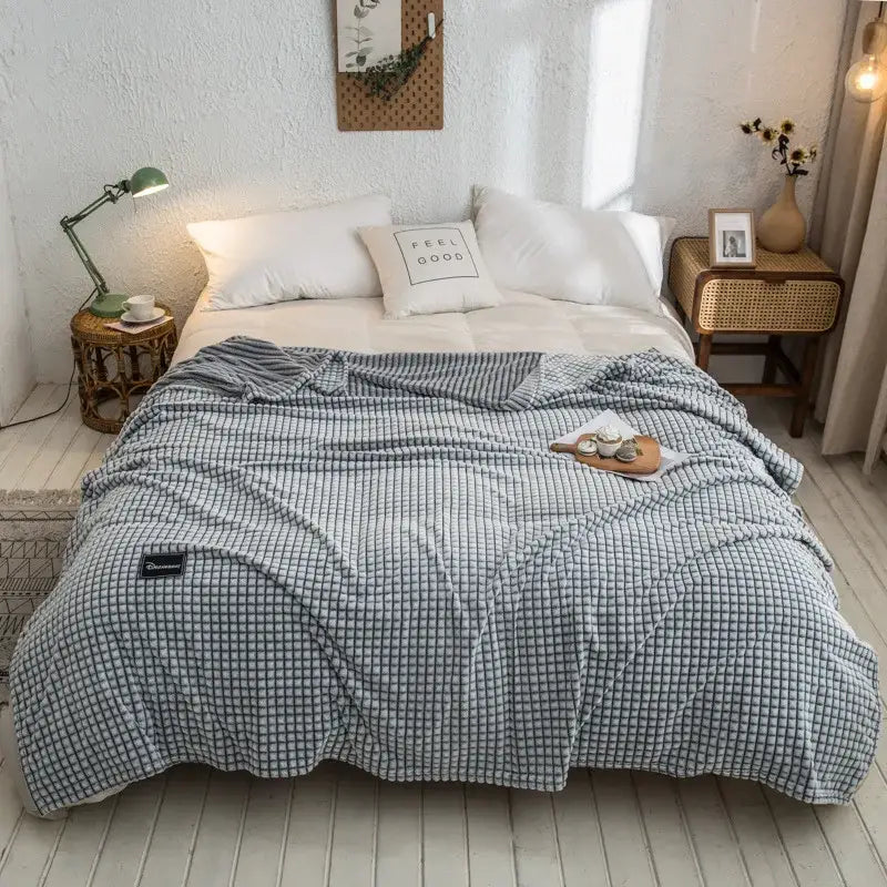 Gray plaid coral fleece bed blanket with soft textured surface in gray and white checkered pattern for bedroom use