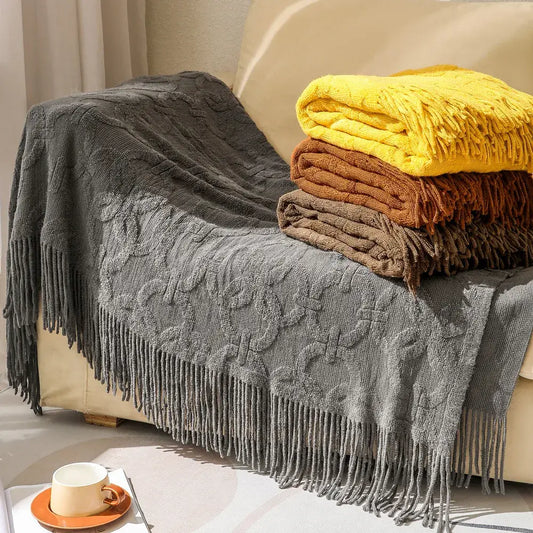 Gray cable knit blanket sofa throw with textured cable pattern and fringe displayed with decorbites knit blanket stack