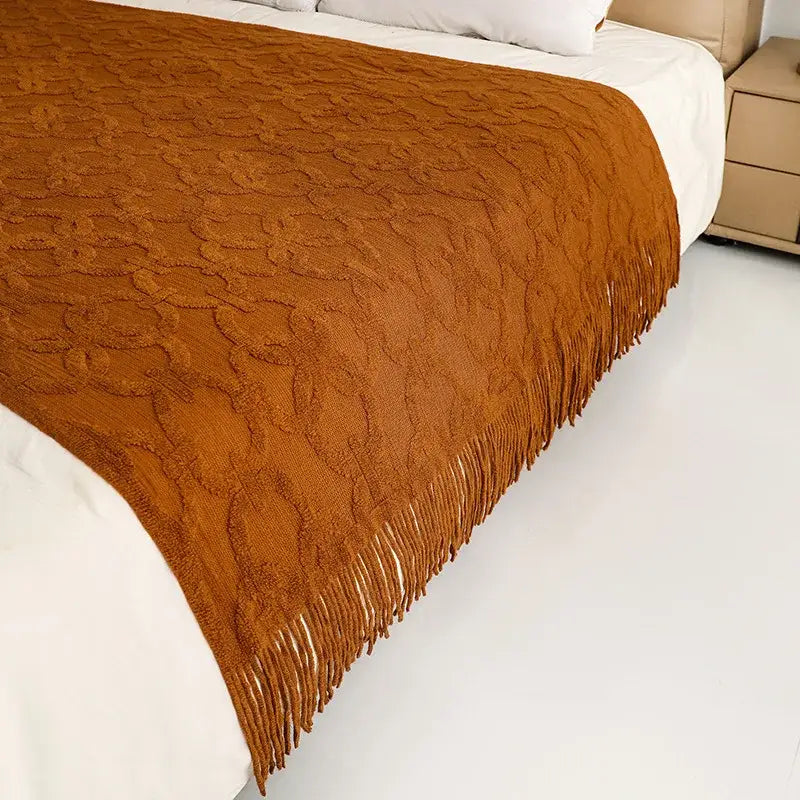 Warm amber-colored knit blanket with textured floral pattern and tasseled fringe for knit blanket sofa decorbites decor