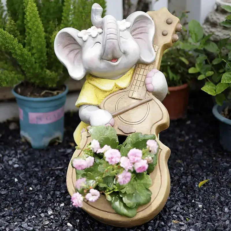 A charming white ceramic elephant garden decoration wearing a yellow shirt holding a guitar-shaped planter with pink flowers