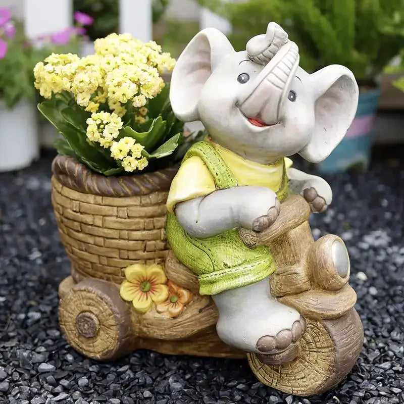A white ceramic elephant garden decoration with a green vest riding a wooden tricycle with yellow flowers