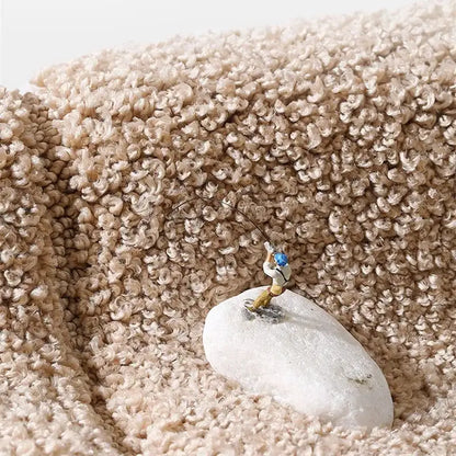 Miniature fisherman figurine on a smooth white stone displayed on a gray geometric flocked bath mat decorbites rug