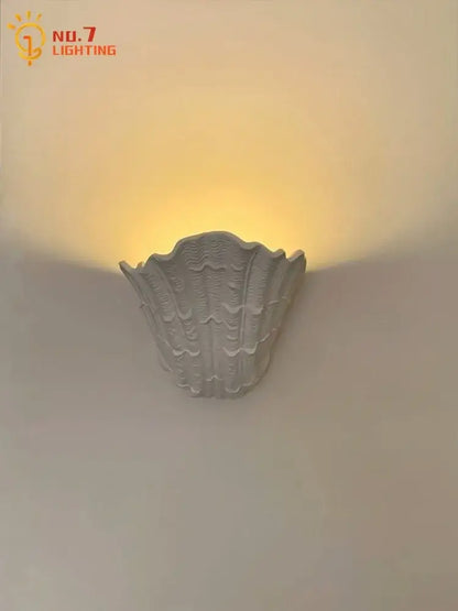 Gray gypsum shell led wall lamp with textured ridged surface designed as a shell-shaped bedroom sconce