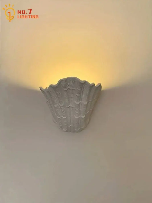 Gray gypsum shell led wall lamp with textured ridged surface designed as a shell-shaped bedroom sconce