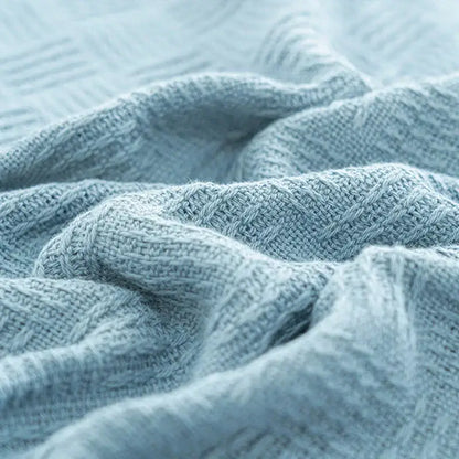 A soft light blue knitted decorbites cotton waffle towel quilt with textured weave for bedroom or office decor
