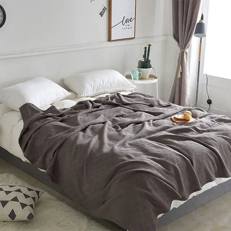 Gray herringbone cotton waffle towel quilt draped over bed with soft textured pattern for bedroom or office decorbites cotton waffle