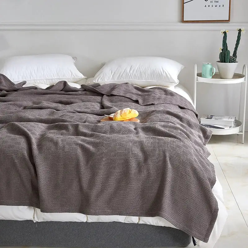 Gray herringbone cotton waffle towel quilt draped over bed showcasing soft textured decorbites cotton waffle design