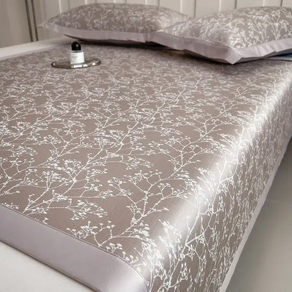 Beige satin bed sheet with delicate white floral embroidery in a gray and lavender branch pattern bed mat set for cooling