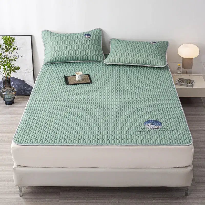 Mint green quilted latex bed mat with subtle mountain embroidery and white piping edges in a bed mat set