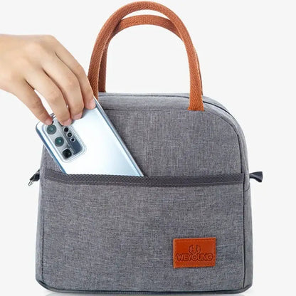 Gray textured insulated lunch bag with brown leather handles and brand patch designed for kitchen thermal use