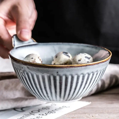 A rustic gray ceramic bowl with vertical ridges and gold rim from a ceramic wedding tableware set by decorbites