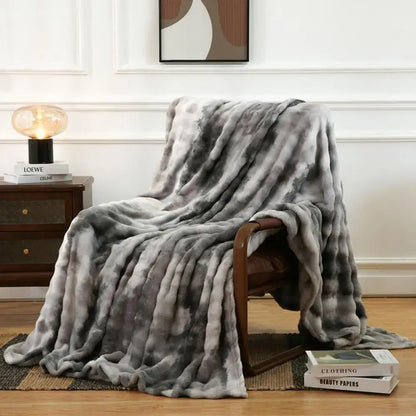 A gray and white tie-dye fuzzy faux fur blanket draped over a wooden chair showcasing decorbites fuzzy faux fur texture