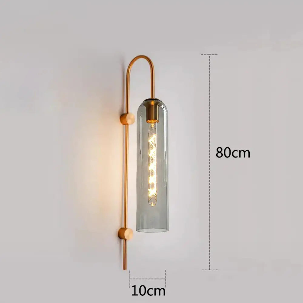 A modern wall-mounted sconce with brass frame and gray glass complements a green glass nordic pendant light