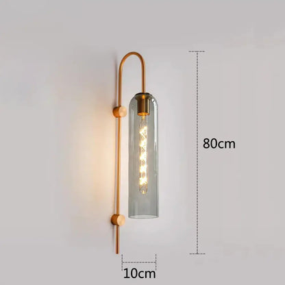 A modern wall-mounted sconce with brass frame and gray glass complements a green glass nordic pendant light