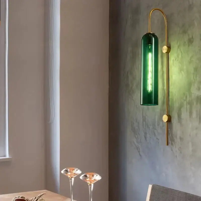A sleek green glass nordic pendant light with amber brass curved sconce and exposed filament bulb for living room