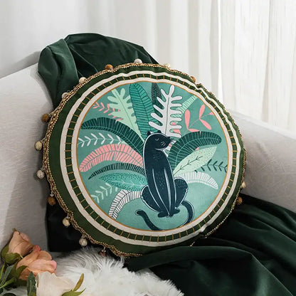 Round cushion cover with black panther and green leaves moss printed on teal velvet framed by dark green velvet and gold pom-poms