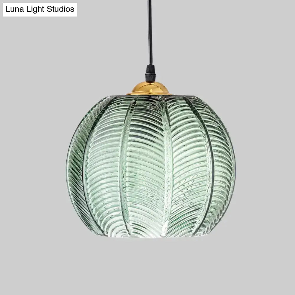 Green ribbed glass pendant lamp with translucent pumpkin shape and brass fixture for dining room lighting