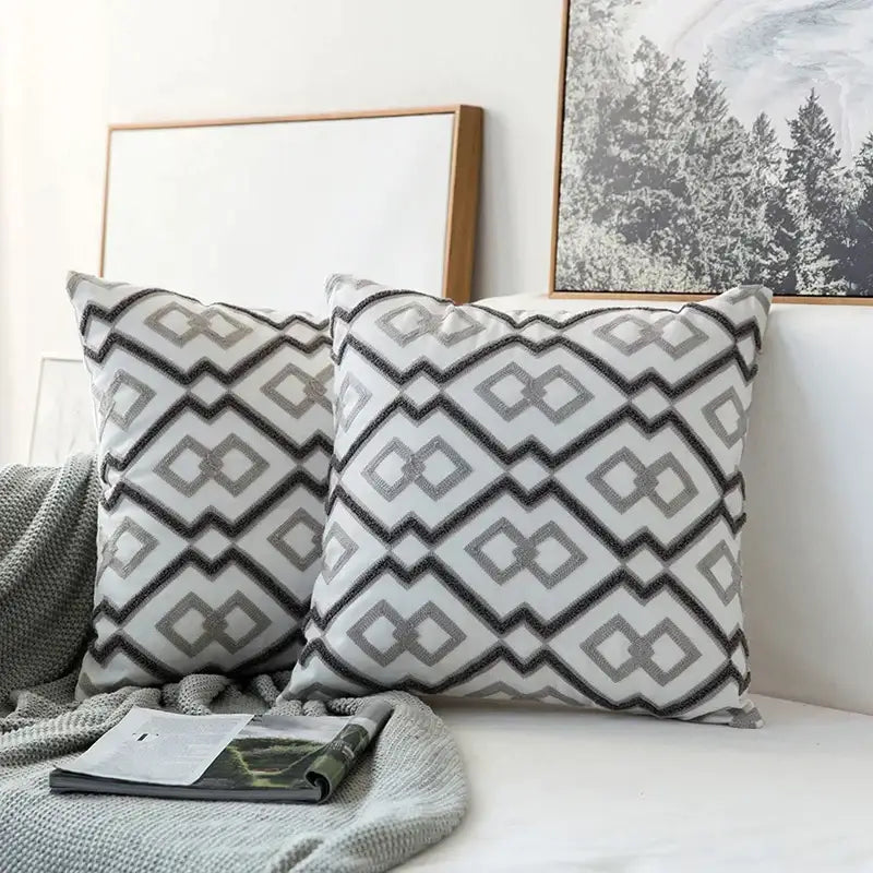 Two matching cushion covers with grey geometric embroidered zigzag diamond pattern on textured white fabric for living room decorbites