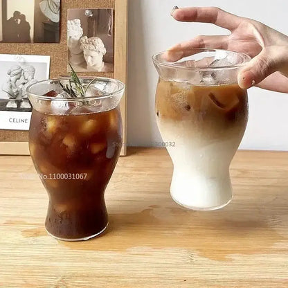 Hammered clear glass cafe coffee cup tumbler with flared rim filled with iced coffee garnished with rosemary decorbites glass cafe