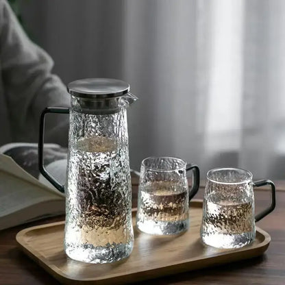 Clear hammered glass water pitcher with sleek black handle and stainless steel lid with two matching textured glasses decorbites gray amber