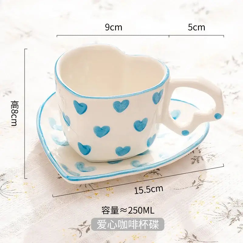 White ceramic love mug with hand painted heart handle blue heart patterns and matching saucer in a heart shape