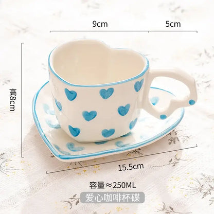 White ceramic love mug with hand painted heart handle blue heart patterns and matching saucer in a heart shape