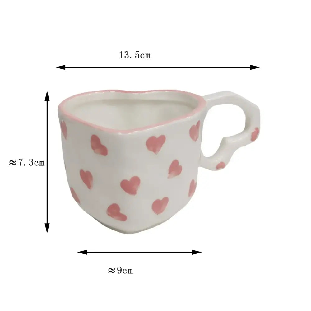 A white ceramic love mug with hand painted heart handle and pink painted hearts paired with a kitchen saucer set