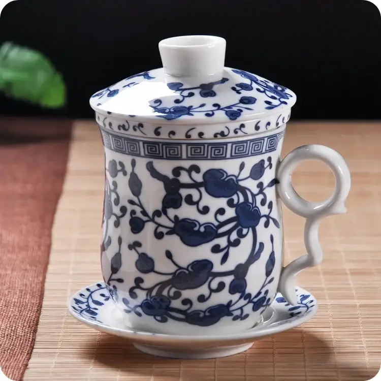 A hand painted lotus white porcelain tea cup with filter featuring intricate blue floral patterns and geometric borders