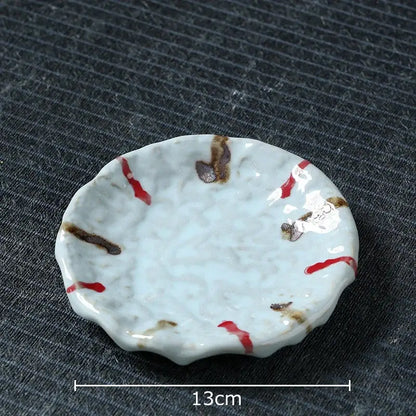 A delicate white ceramic dish with scalloped edge and red brushstroke patterns for hammer pattern ceramic mug set
