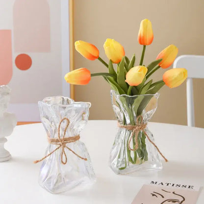 Handcrafted clear glass folded road vase set with textured glass and twine ties holding yellow and orange tulips decorbites clear glass