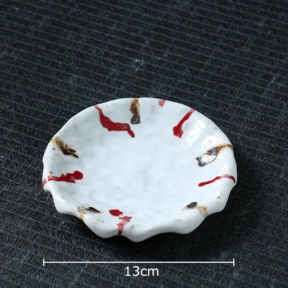 A white ceramic dish with scalloped edge featuring red and brown splatter patterns for hammer pattern porcelain set