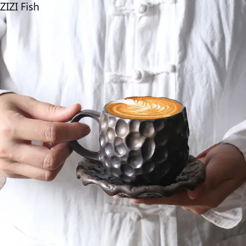 Black hammered ceramic mug with matching saucer featuring textured hammer pattern porcelain and latte art