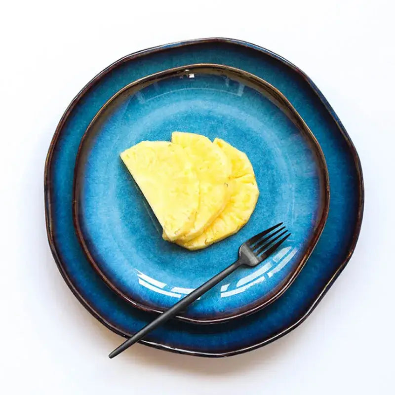 A handcrafted deep blue ceramic dessert plate with rustic finish and dark rim holding pineapple slices from decorbites deep blue