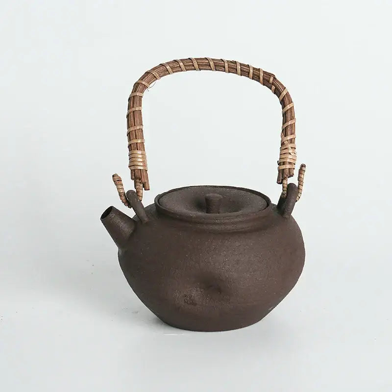 Dark brown cast iron teapot with woven bamboo handle and spout for handmade capybara carbon oven surrounding stove tea warmer