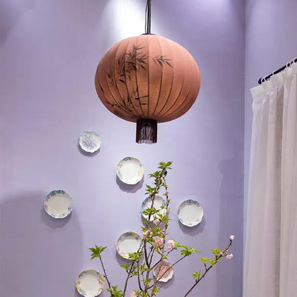 A peach and cream handmade decorbites bamboo lantern pendant with black bamboo leaf designs and dark fringe for dining room light