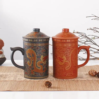 Two ceramic tea mugs with lids in dark gray and terracotta orange featuring golden dragon decorbites dragon purple clay designs
