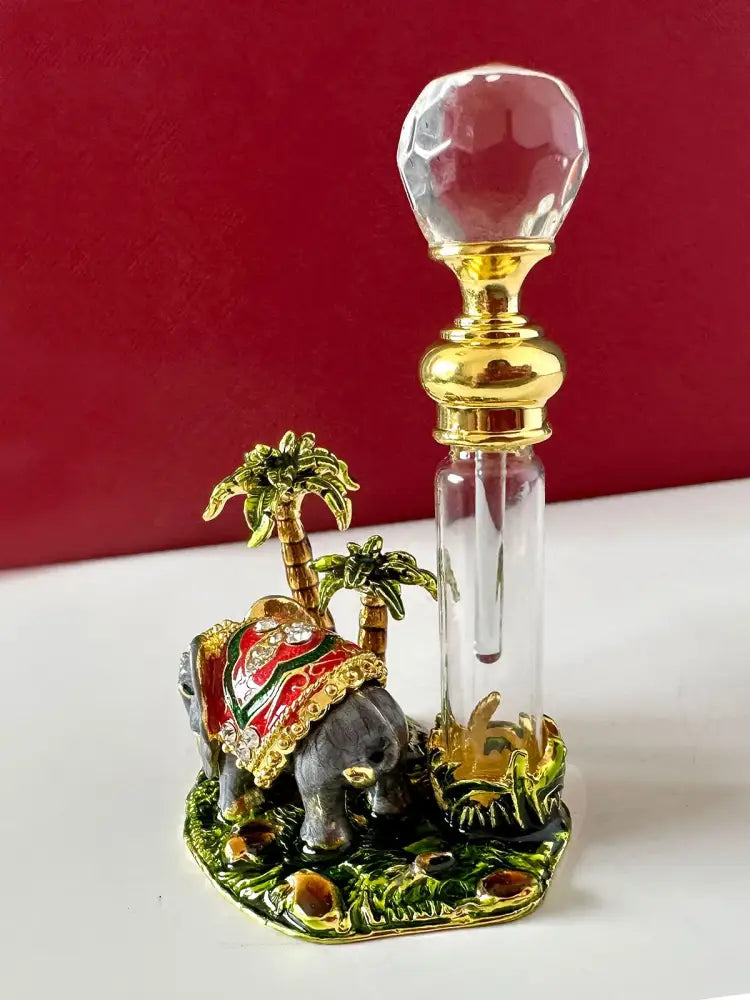 Handmade red and gold crystal perfume bottle with faceted stopper on ornate enamel elephant bedroom decor