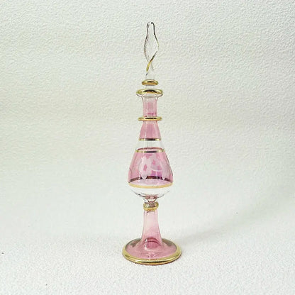 A delicate pink handmade glass bottle with gold accents and an ornate stopper as an exquisite ornament for living room decor