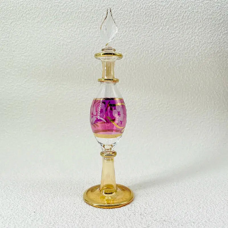 A slender handmade glass bottle with gold stopper and pink floral design as an exquisite ornament for decor