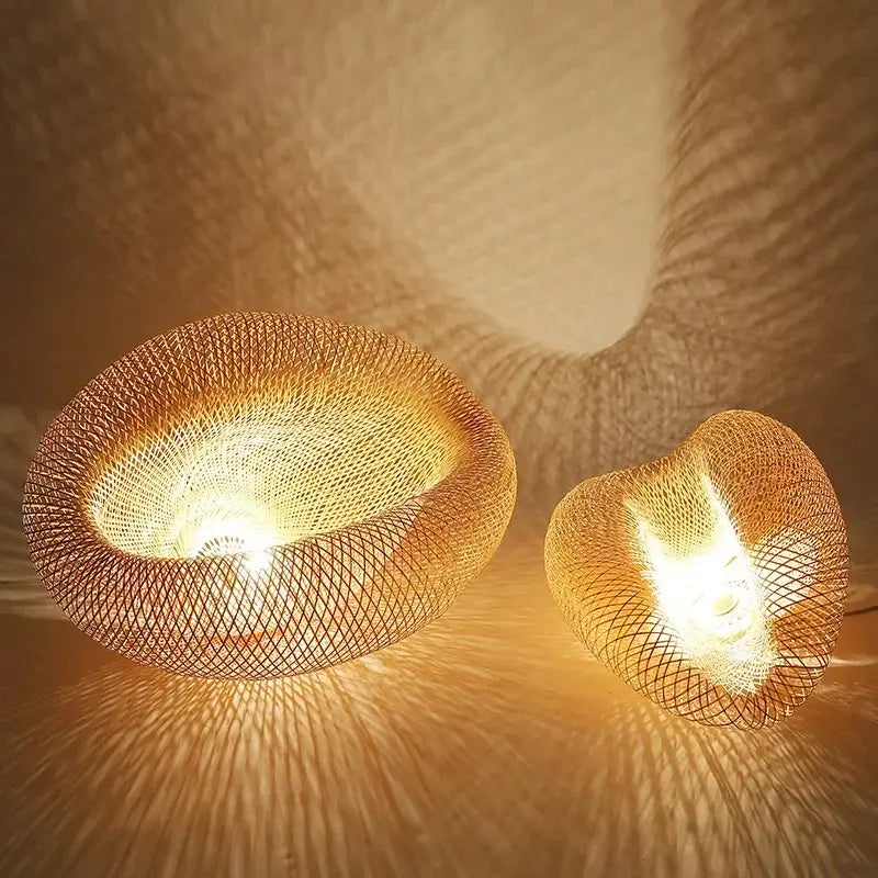 Two warm-toned golden brown bamboo wave pendant lights with woven wire mesh casting soft patterned light for dining room