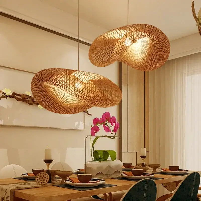 Two golden brown handmade bamboo wave pendant lights with organic design hang above the dining table