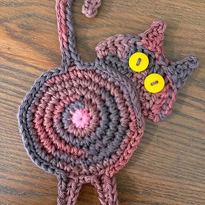 Handmade gray crocheted cat butt coaster in pink and gray with yellow button eyes from decorbites cat butt coasters set