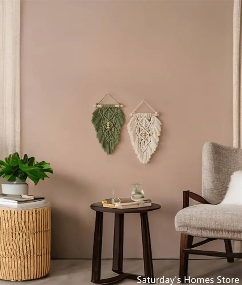 Two handmade macrame leaf wall hangings in olive green and off-white with intricate woven patterns and wooden hangers
