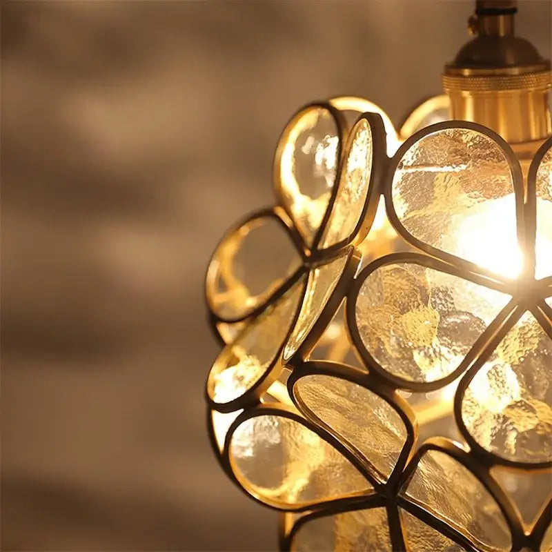 Golden flower-shaped pendant light with brass framing and textured glass panels in a handmade glass petal pendant design