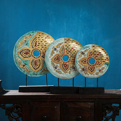 Three ornate handmade thai solid gold and red mosaic circular plaques tabletop decoration on teal background