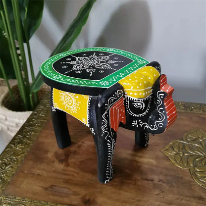 Hand-painted decorbites elephant stool with black base, vibrant yellow red accents, and intricate white floral patterns