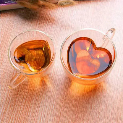 Two clear glass heart love double walled coffee mug cups filled with amber liquid for kitchen drinkware use