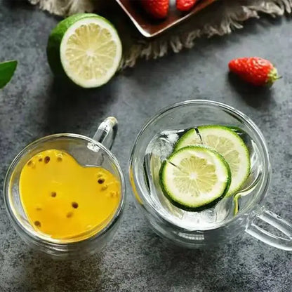 Two clear heart love double walled glass coffee mug cups with yellow passionfruit drink and ice water lime slices