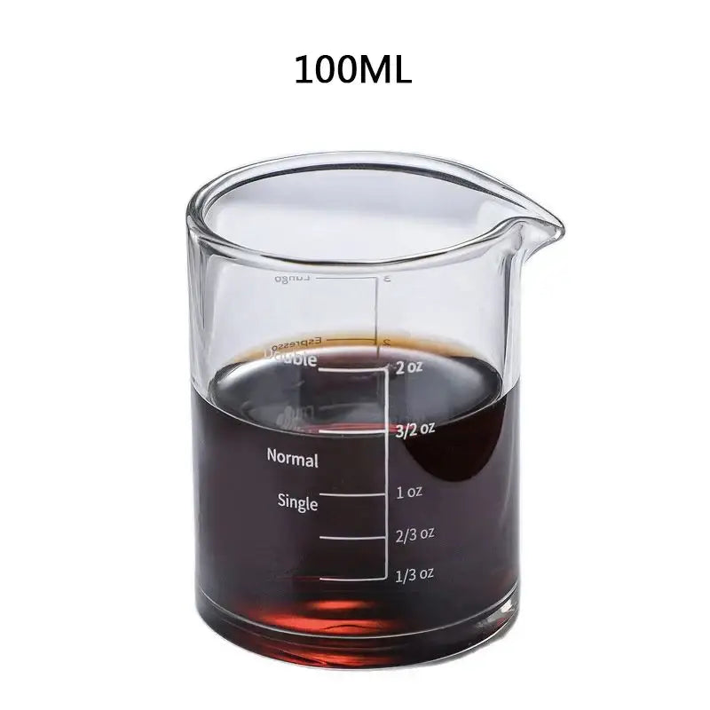 A clear heat resistant glass espresso milk jug with wood handle and 100ml measurement for precise coffee servings